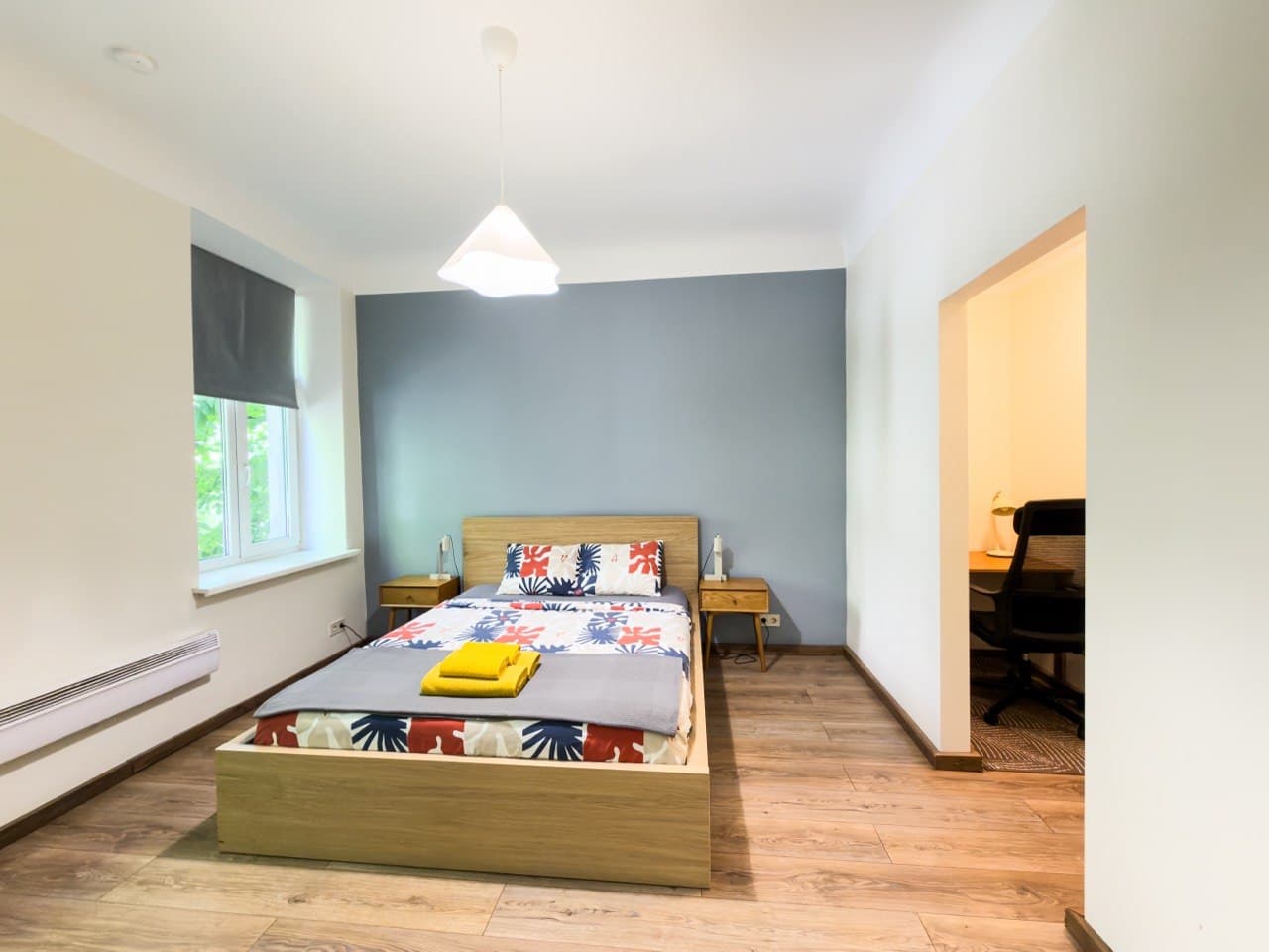 Bedroom with double bed, blue accent wall, and workspace nook