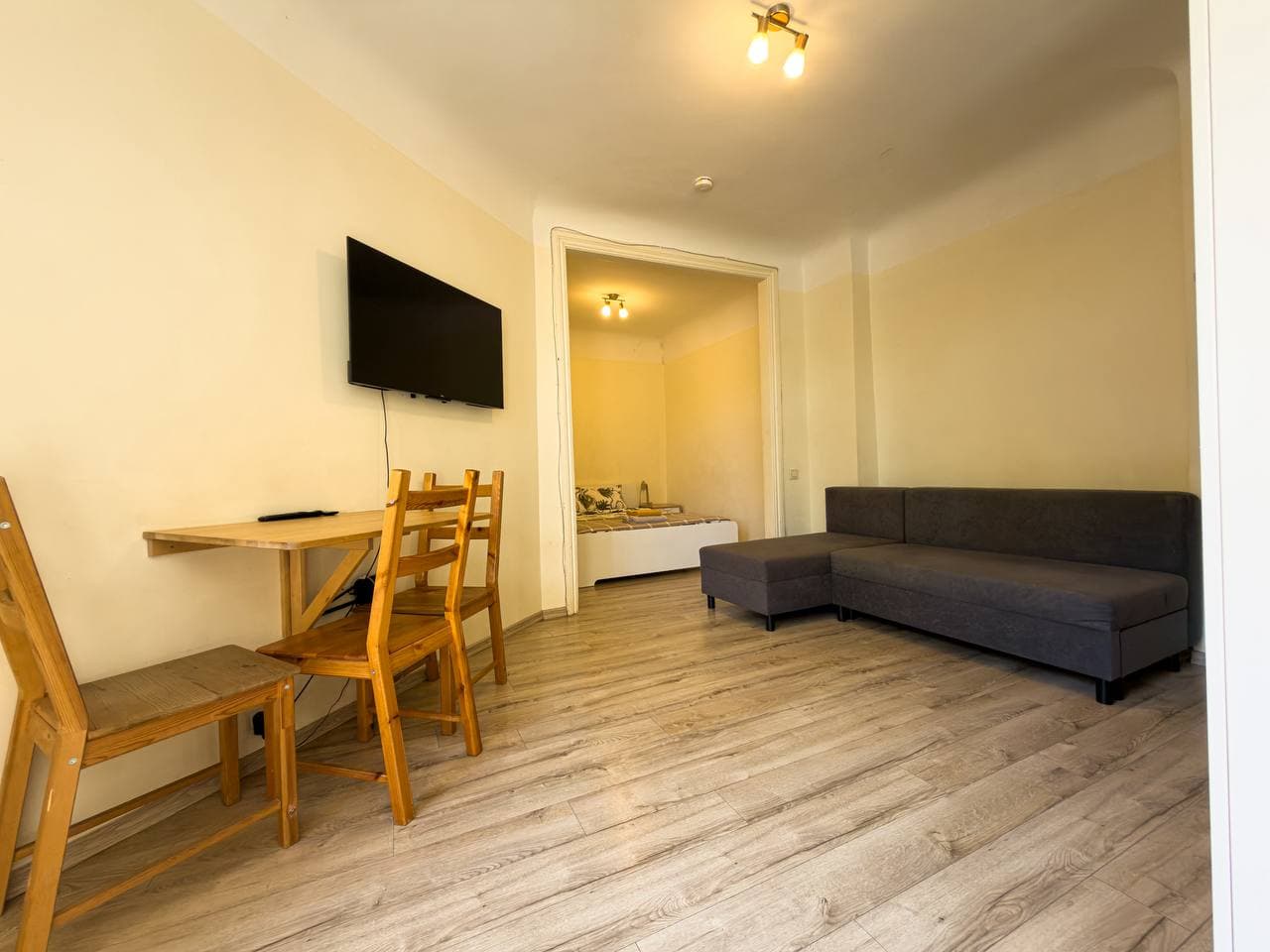 Living area with sofa, dining table, and bedroom doorway